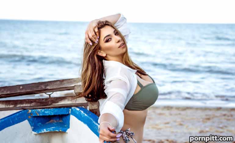 Affair Fog Online: Protecting Your Privacy and Legal Rights Now Woman in a green bikini top and white cover-up posing by a small blue-and-white boat on a sandy beach with the ocean in the background.